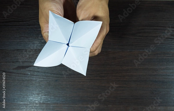 Fototapeta The man's hand is holding a paper that predicts the fate known as Paper Fortune Tellers. To predict the future, work, love, fate, sometimes used as a fun game to play. There is space for copy space.