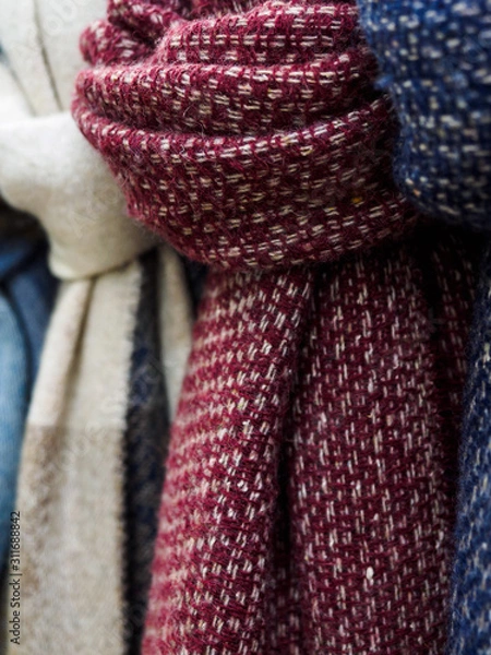 Fototapeta Wool scarves hang in the shop window. Colorful scarves tied in a knot