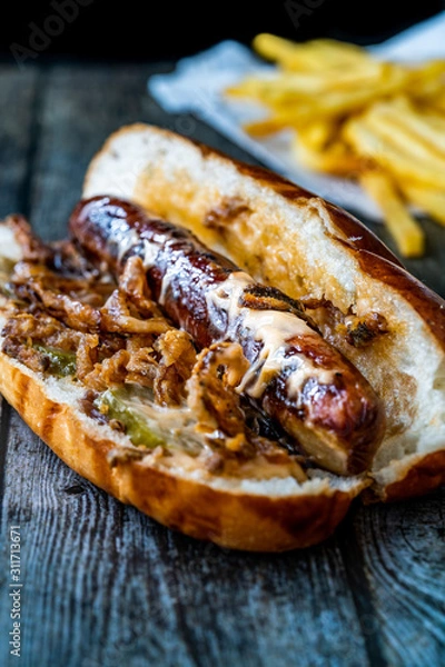 Fototapeta Hot Dog with Caramelized Onion, Cheddar and Gruyere Cheese Sauce on Wooden Surface with Potatoes.