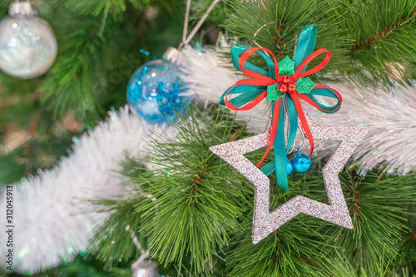 Obraz Beautiful Christmas star hanging from a decorated Christmas tree