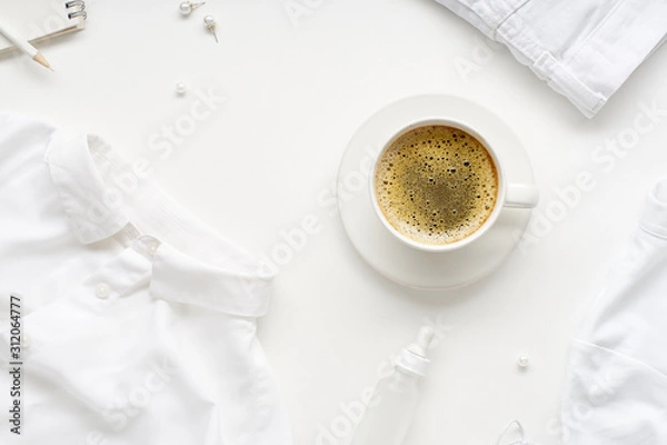 Fototapeta Creative flatlay with monochromatic white clothes and accessories and a cup of coffee on white background. No stain concept
