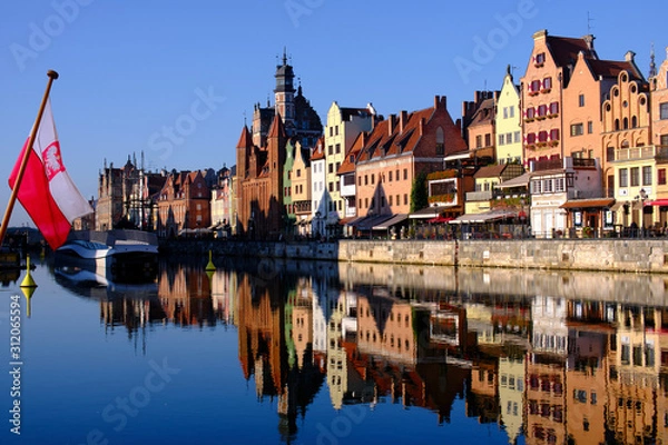 Fototapeta Colorful hanseatic city facades of historic houses close to the Motława river in Gdansk, a port city on the Baltic coast of Poland, in the foreground a polish flag