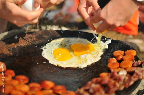 Fototapeta Two eggs cooking over a fire