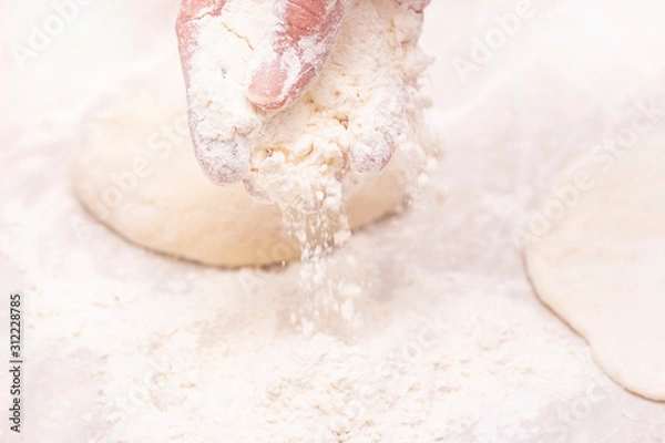 Fototapeta Womens hands, flour and dough. A woman is preparing a dough for home baking. Flour the dough and table. concept of home cooking