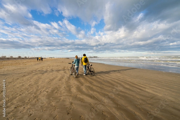 Fototapeta two person are doing a walk on winter beach