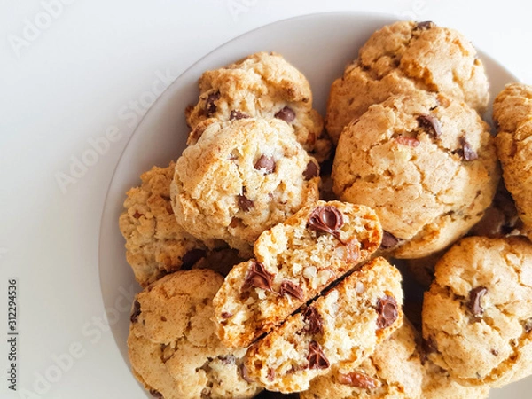 Fototapeta Homemade oatmeal cookies with pecan nuts and milk chocolate on a light grey plate on a white background