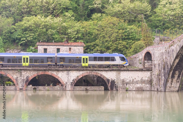 Fototapeta Bridge of a devil. Bridge over the river in Tuscany. Built in the 11 century. The train passes under the bridge.