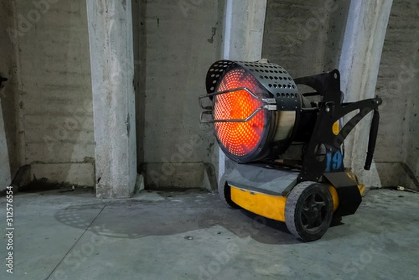 Fototapeta Heavy duty industrial heater blowing hot air in cold building interior. Heat compressor or heat fan propeller, propelling warm air in cold constructions