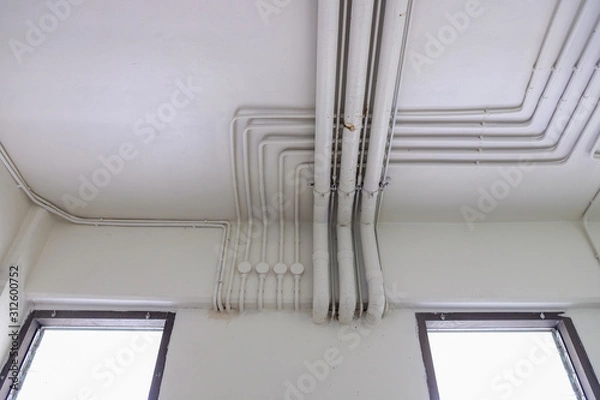 Fototapeta Electrical system pipes and water system pipes. White electric PVC pipes line or Wiring rails in the building