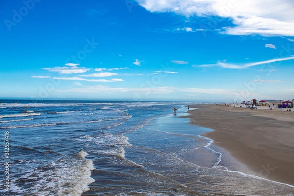 Fototapeta Mar bravio com ondas e o céu azul com nuvens na Praia dos Molhes, cidade de Torres, estado do Rio Grande do Sul, Brasil