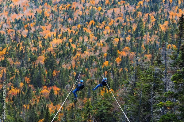 Obraz two people sliding down very long and fast zipline during autumn in Stowe, Vermont