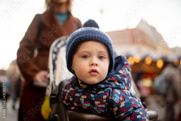 Fototapeta Littl boy sitting in a stroller and looking in camera