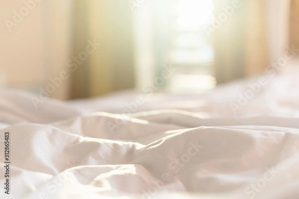 Fototapeta White bedding sheets and pillow in hotel room at morning time with sunlight from windows