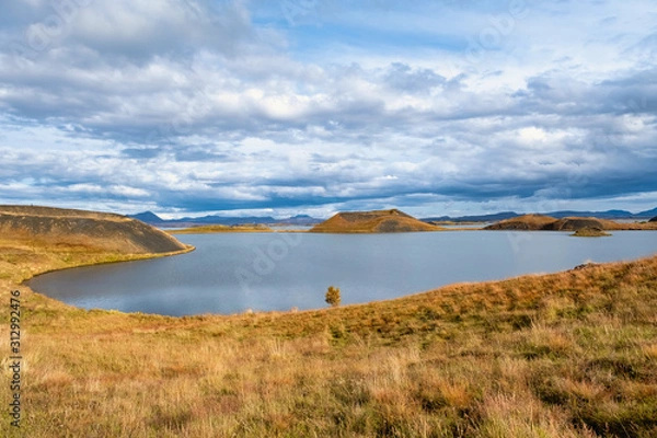 Fototapeta The lake of Myvatn is surrounded by mountains with a beautiful sky