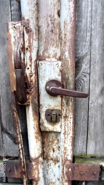Fototapeta Handle and rusty lock in wooden wicket door close-up
