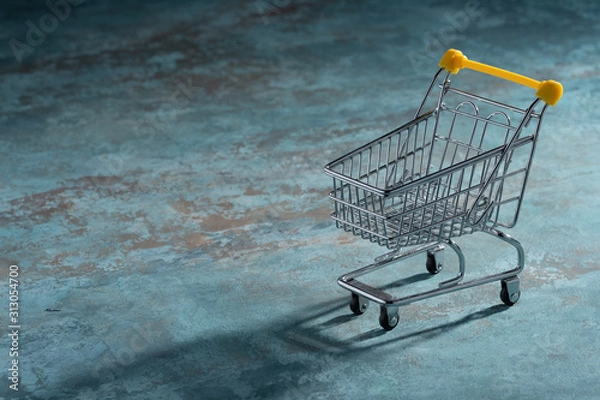 Fototapeta Shopaholic. Buyer. Shopping concept. Close-up. An isolated trolley and shopping basket on a textural navy blue background bisected
