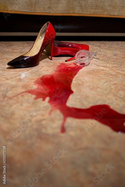 Fototapeta A spilled glass of wine and women's shoes on the floor.