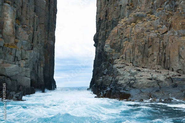 Fototapeta Water flowing through a rock formation, with seals on the cliff face. 