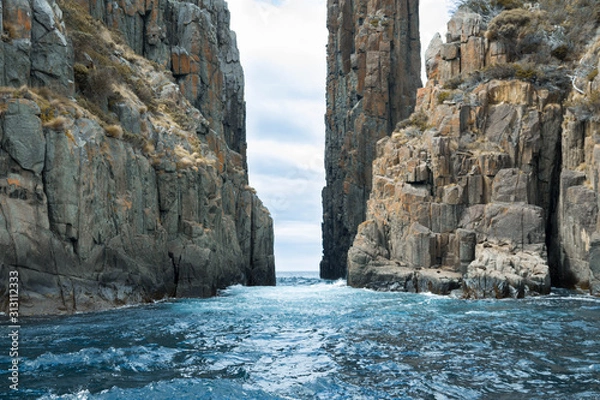 Fototapeta Water flowing through a rock formation, with seals on the cliff face. 