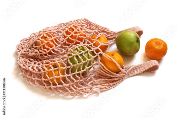 Fototapeta Peach Coloured Hand-Made Crochet Eco-Friendly String Shopping Bag with Green Apples and Tangerines  on White Background. Concept of Ecology, Environmental Protection & Zero Waste