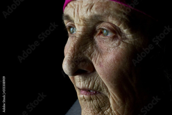 Fototapeta Old face with wrinkles closeup. Grandmother's face close-up. Eyes close-up on the face of an old grandmother. Portrait photo of an old mother