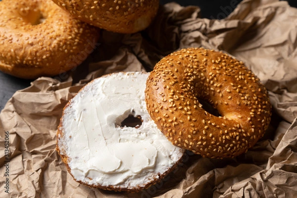 Fototapeta Sesame bagels with spreadable cream cheese on dark background