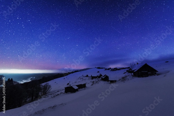 Fototapeta Fairytale landscapes of the winter Carpathian Mountains with a charming milky way in the sky tourist tents and snowy houses in the valleys
