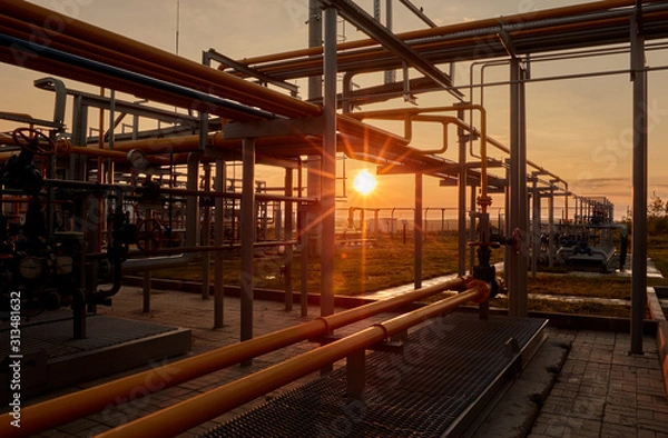 Fototapeta Gas industry. Pipeline system at gas processing plant illuminated by the rays of the rising sun