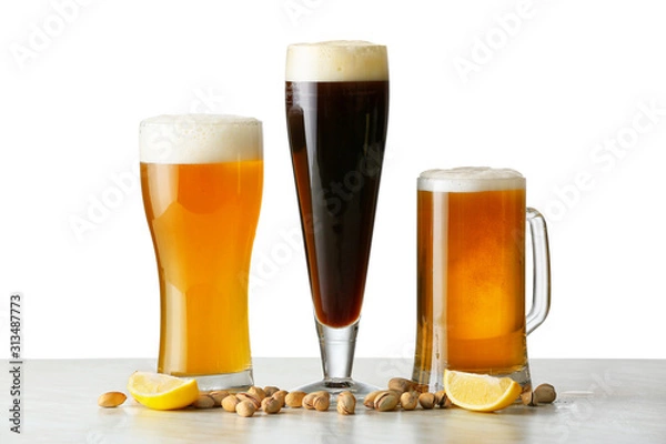 Fototapeta Glasses of different tasty beer with pistachio nuts on white background