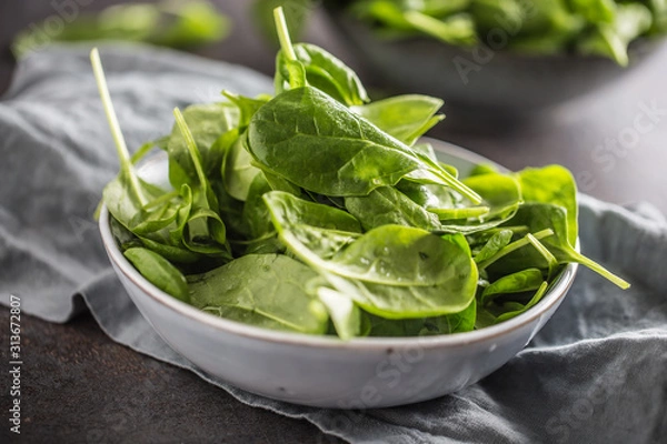 Fototapeta Fresh baby spinach in bowl on dark kitchen table