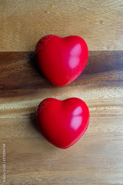 Fototapeta two red hearts on a wooden background 