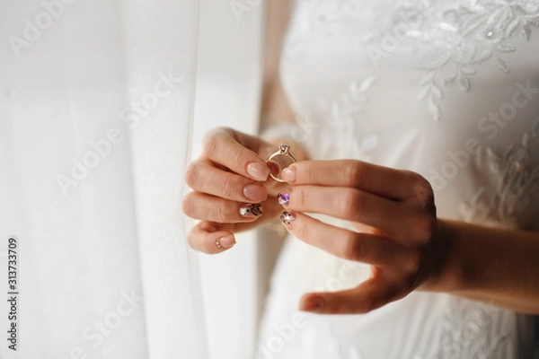 Fototapeta beautiful bride holds a wedding ring with a diamond in her hands