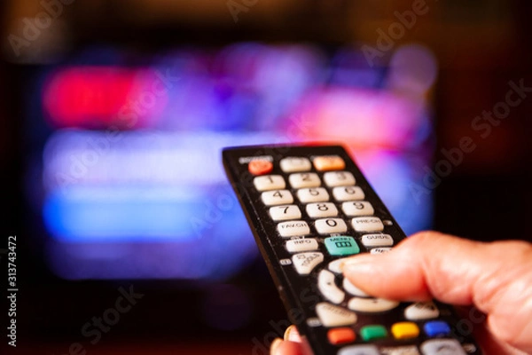 Fototapeta Hand mit Fernbedienung vor großem Bildschirm Netflix auswählen 