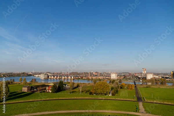 Fototapeta Skyline from vinex neighbourhood Barendrecht Carnisselande and Rotterdam at the background, taken from â€œGaatkensbultâ€ with a blue sky.