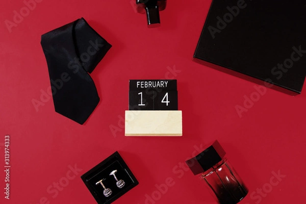 Fototapeta Composition of black neck tie, arm buttons, two perfumes and a gift box  on red  background. Top view. Man's fashionable style concept. Gift for men.