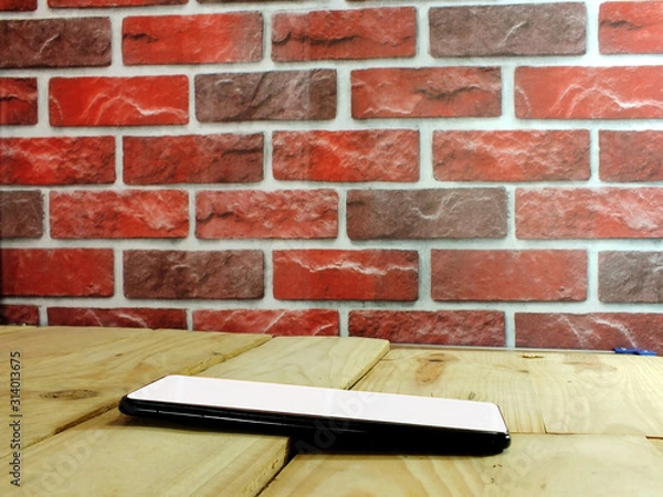 Obraz A white screen smartphone placed on a wooden office desk