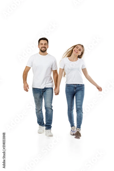 Fototapeta full length portrait of happy couple in casual outfit walking forward together on white background