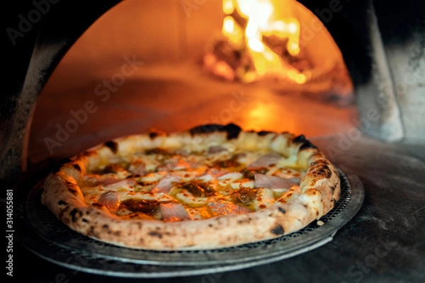 Obraz Freshly baked pizza on the background of a burning wood-burning stove