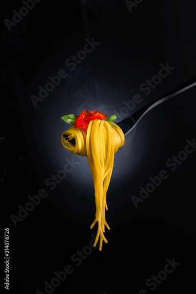 Fototapeta Spaghetti with tomato sauce and basil on a fork, with steam. Close-up shot, shallow focus.