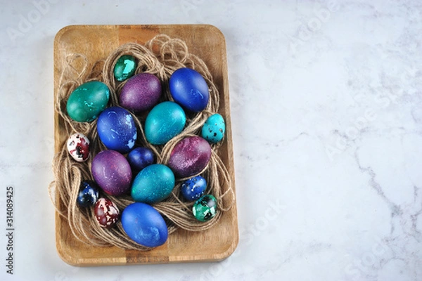 Fototapeta Easter eggs on a wooden tray. Eggs are green, blue and purple. View from above. Close-up. Free space for text.