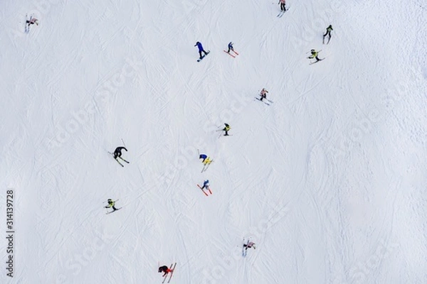 Obraz Aerial drone view on skiers on ski slope at winter.