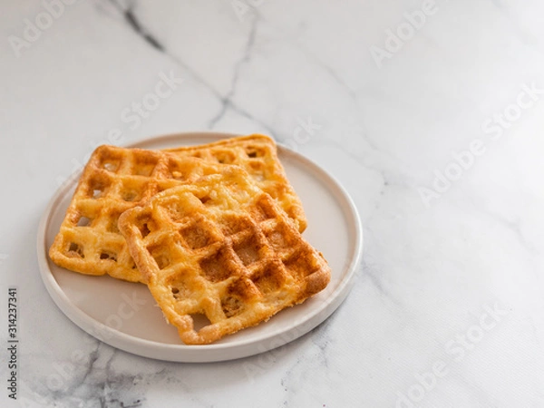 Fototapeta Delicious savory keto waffles. Two ingredients chaffles on plate over white marble background. Eggs and parmesan cheese low carb waffles. Copy space for text or design.