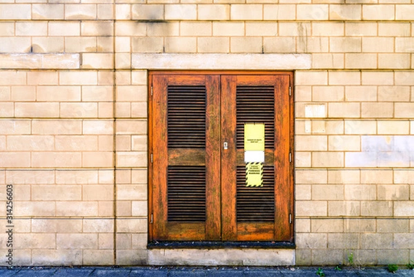 Fototapeta danger high voltage sign on wooden door on stone brick wall in england uk