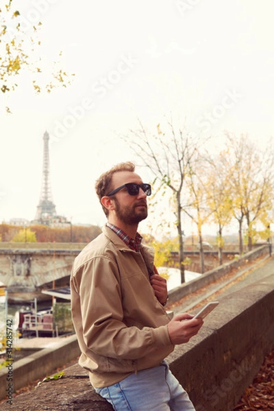 Fototapeta Handsome man using cellphone while enjoying in Paris.