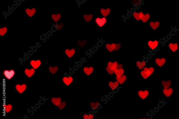Fototapeta Black background with bright red warm heart shaped bokeh lights. Holiday, Valentines Day background. Ideal to layer with any design. Horizontal