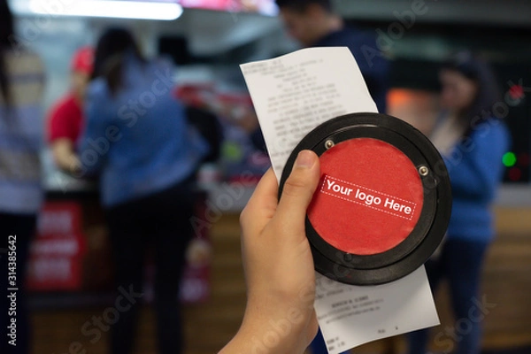 Fototapeta Hand showing Invoice with Wireless calling system restaurant or pager customers system  and person row background.