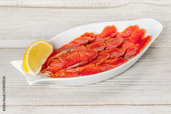 Fototapeta Sliced sockeye salmon on a white plate with lemon