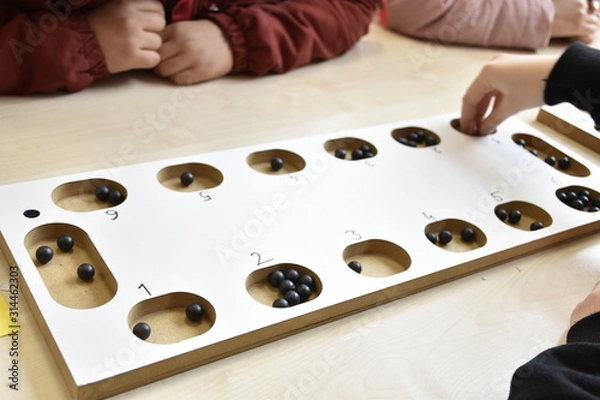 Fototapeta A table game of a beige color on a table: "mangala". and hands of people playing mangala