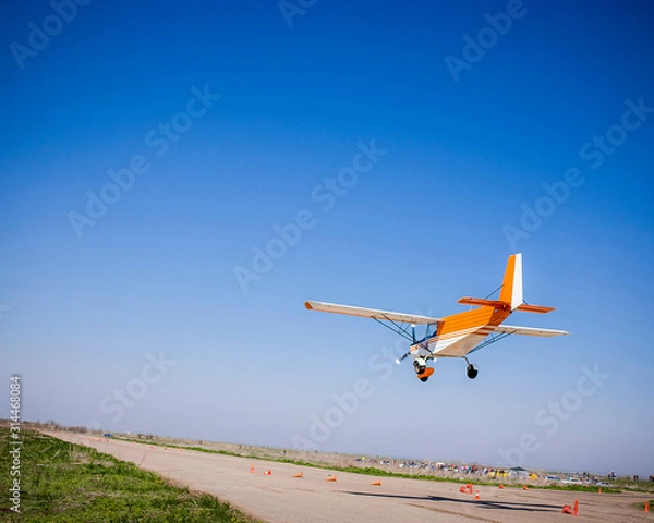 Obraz light single private orange plane in clear blue sky