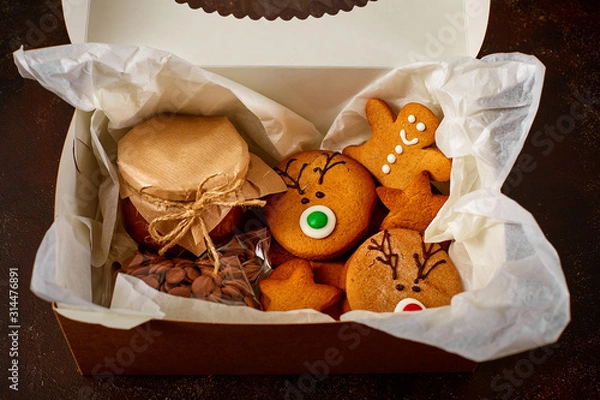 Obraz Delicious curly Christmas gingerbread, caramel in a jar covered with paper and tied with string, chocolate in a package in a gift box